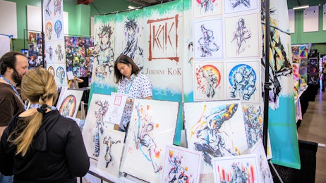 An artist is standing at his table with his art