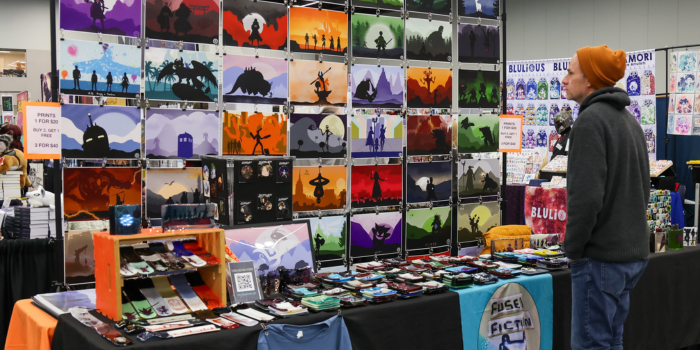 Customer admires colorful prints on display at an event booth.