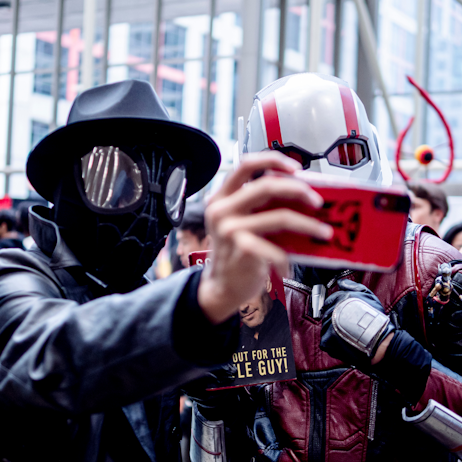 Spider-Man Noire and Ant Man take a selfie using Spider-Man Noire's phone. The case is Transformers and has the Autobots logo on the backside. Ant Man is holding a copy of Scott Lang's book "Look Out For the Little Guy"