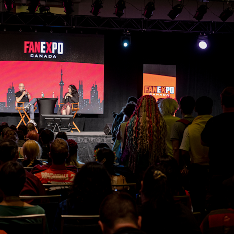 Christopher Sabat answers questions for fans during his panel. Fans are lined up at the microphone in the centre of the room, waiting patiently to ask their question as they watch the panel.