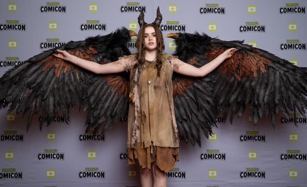 A cosplayer dressed as Maleficent extends her wings.