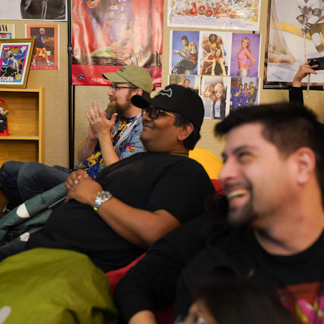 Fans  watch eagerly as the screening of X-Men '97 begins. Around them is posters for various 90s pop culture favourites