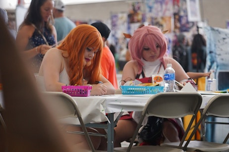 Two fans draw while sitting at a table