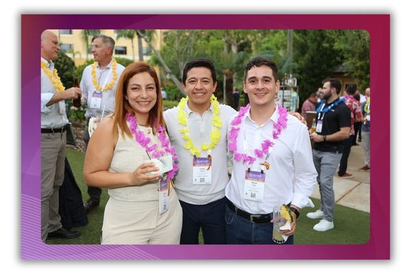 Three people standing and smiling for the camera at a networking event