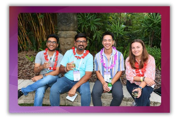 A photo of four people wearing leis smiling and posing.