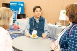 Group of 3 having a discussion at a table at the healthcare waste conference