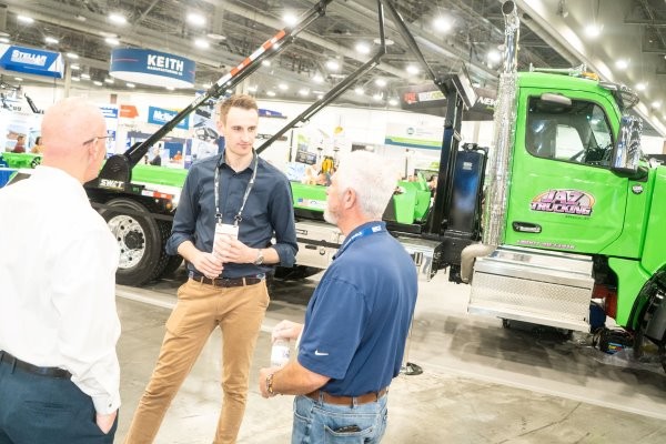 Wastexpo attendee discussing products with an exhibitor in front of a large touchscreen