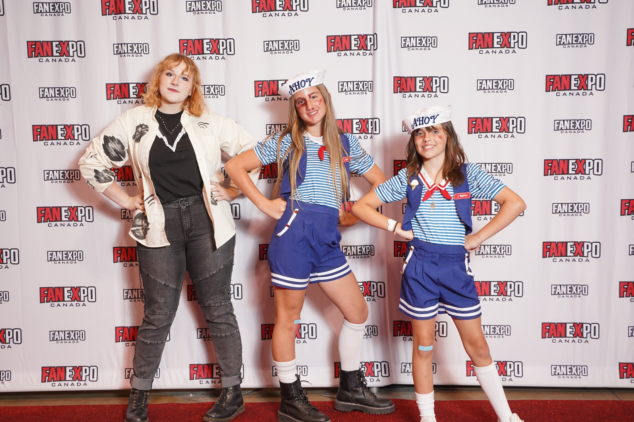 Three girls pose in Stranger Things cosplay on the red carpet at FAN EXPO Canada