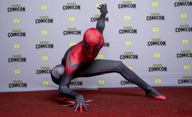 A cosplayer dressed as Spider-Man hits Spider-Man's iconic crouch on the red carpet