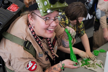 A fan in Ghostbusters cosplay plays with green slime