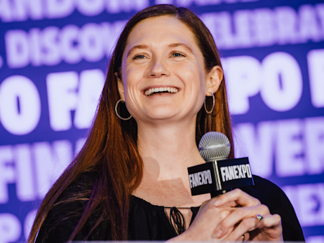 Bonnie Wright smiling, holding a microphone.