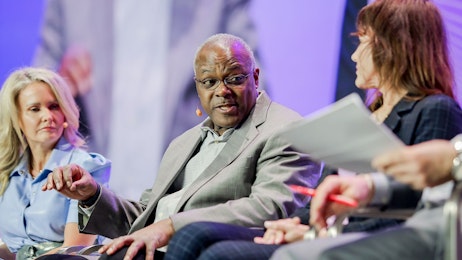 Two wome and a man sitting and speaking onstage