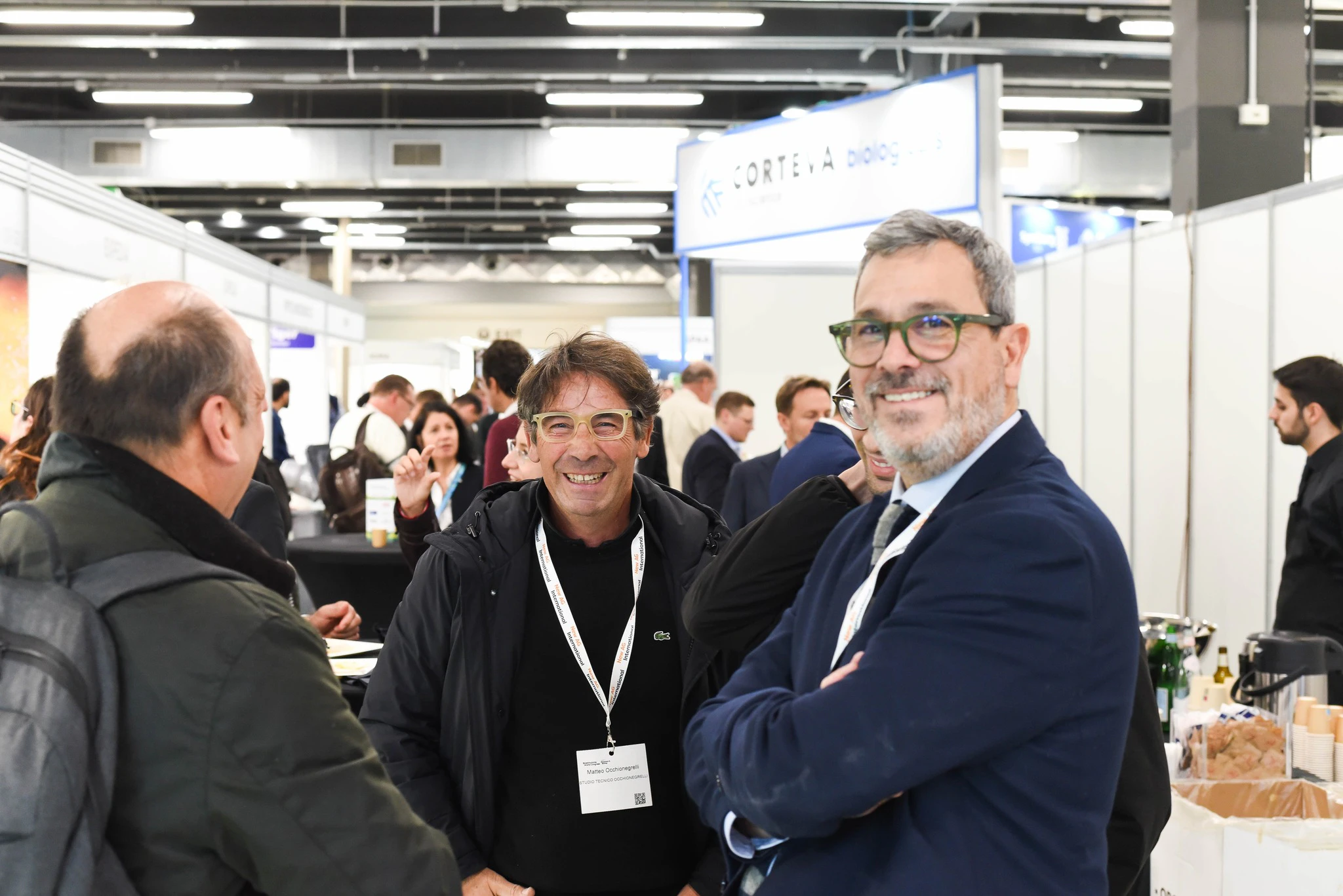 3 delegates smiling at the photographer during last year's networking reception in Milan
