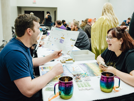 A fan (left) and a woman (right) playing a tabletop game together and laughing