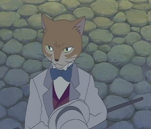 Baron Humbert Von Gikkingen, the character from The Cat Returns is standing against a wall of rocks. He is wearing a grey suit with a maroon vest underneath and a blue bowtie. He is holding a grey top hat and has a cane in his hand.