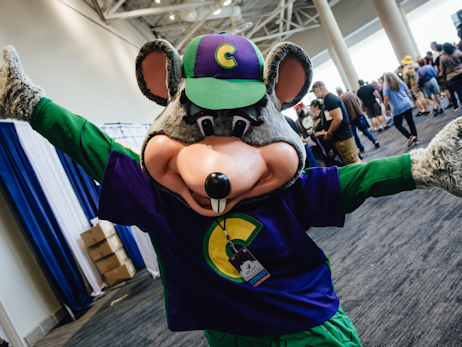 A Chuck E. Cheese cosplayer holding his arms out to the side and smiling for a photo