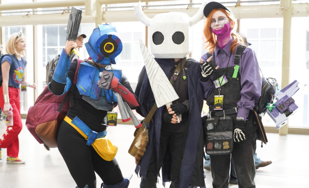 Three cosplayers from different games pose together on the expo floor.