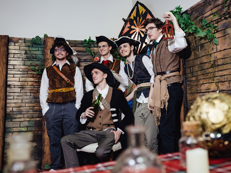 a group of five men dressed as pirates posing for a group photo with a D&D background.