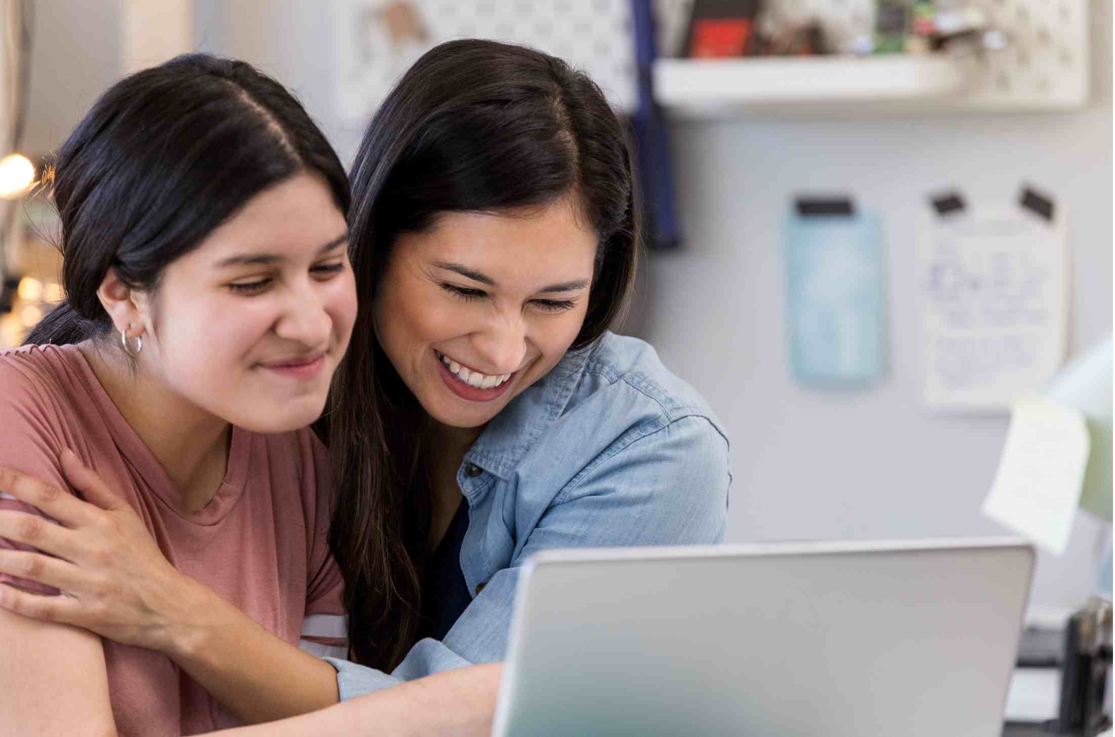 Two students smiling in front of laptop