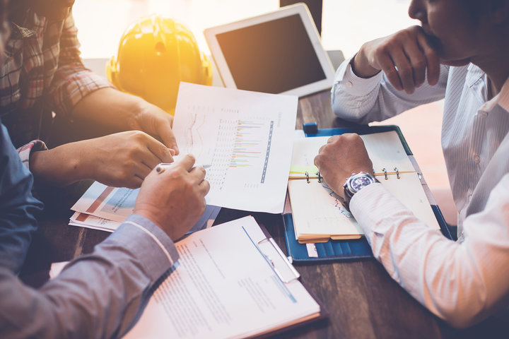 Three business people serious and working hard together in the office with budget and data for new business construction project.