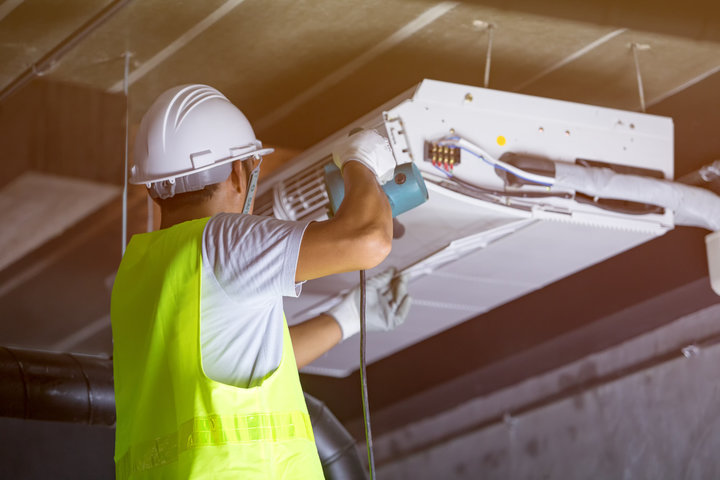 Construction worker in fluorescent vest fixing air conditioning unit