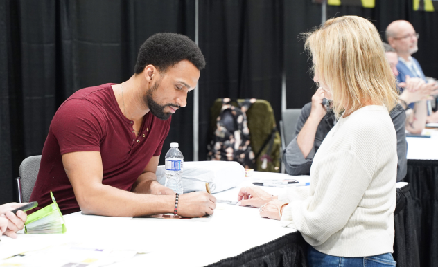 Nathan Mitchell smiles as he signs an autograph for an eager fan.