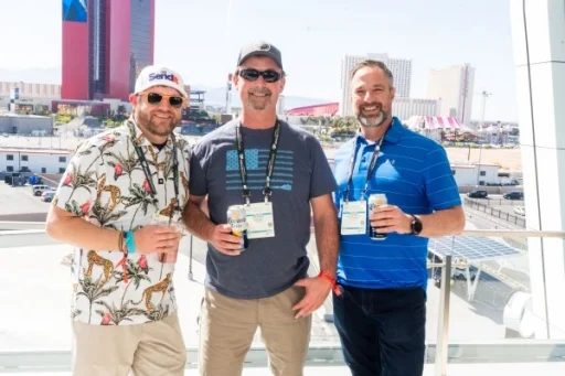 3 men posing for a photo in front of the Vegas skyline at the public sector reception
