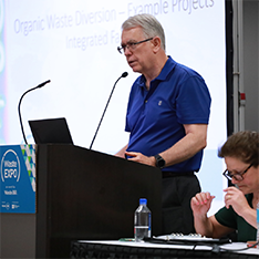 Speaker presenting in front of a mic at an Organics Recycling Session