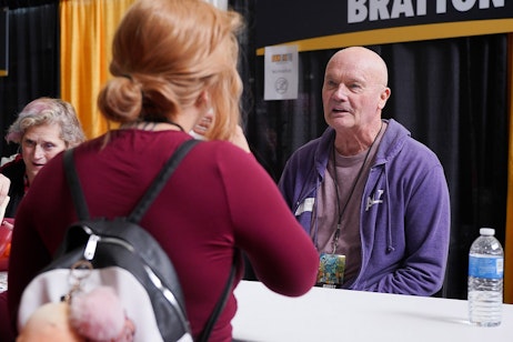Creed Bratton speaks to a fan at his table