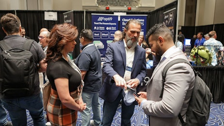 Three people talking to one another in a busy expo hall