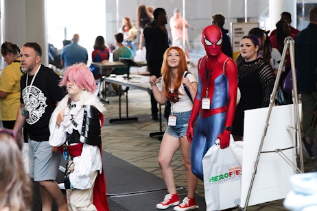two fans dressed as spider-man and mary jane enter the show floor
