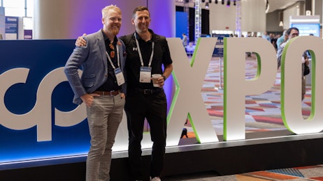 Two men posing in front of a structure that says CPExpo
