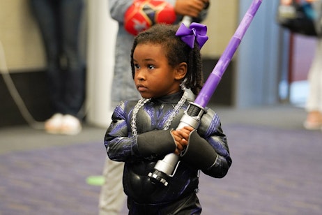 A very young fan holds a purple lightsaber