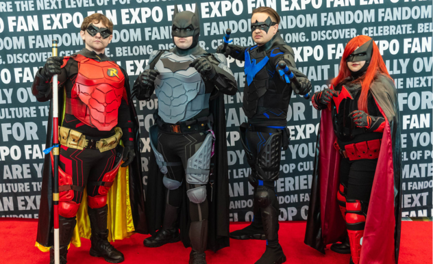 The image shows four individuals in costumes that are reminiscent of a group of vigilantes from a comic book series, known for their nocturnal themes and crime-fighting prowess. From left to right, the first individual is wearing a costume with red accents and an "R" emblem on the chest, suggesting a sidekick or partner character. The second is clad in a grey and black suit with a cowl, emblematic of a caped crusader. The third person's costume is blue with black accents, equipped with protective gear and goggles, implying a high-tech approach. The fourth is in a red and black outfit with a cape, possibly representing a female counterpart in the same vigilante group. They stand confidently on a red carpet with their hands on their hips or in other heroic poses, in front of a backdrop promoting the "FAN EXPO," which suggests they are at a fan convention celebrating popular culture.