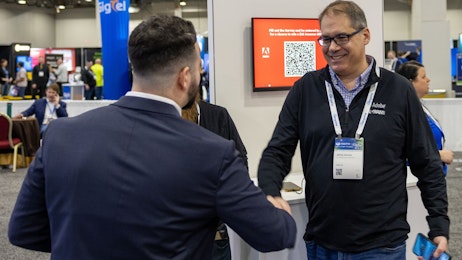 Two men shaking hands in front of a trade show booth