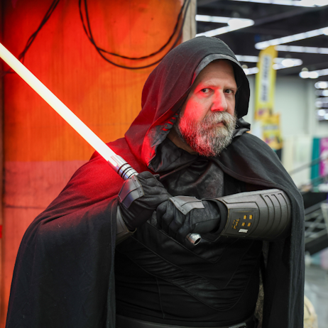 Cosplayer dressed as a Star Wars Jedi with a black cape and red lightsaber