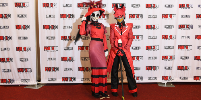 Fans dressed as Alastor and Rosie pose together, Alastor holding his microphone, Rosie tips her hat.
