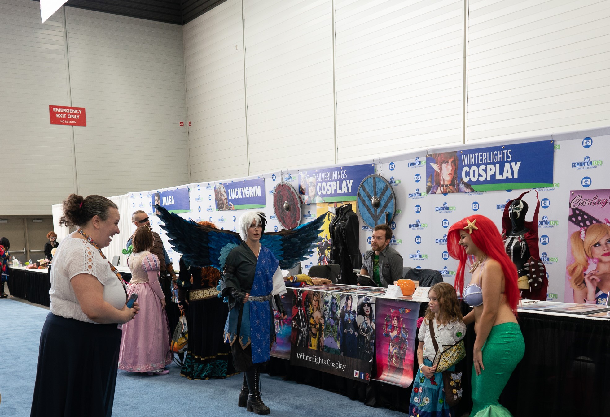 Cosplay guest area. On the left is a mother smiling as her child is dress as Mirabel and posing next to a Cosplay guest as Ariel