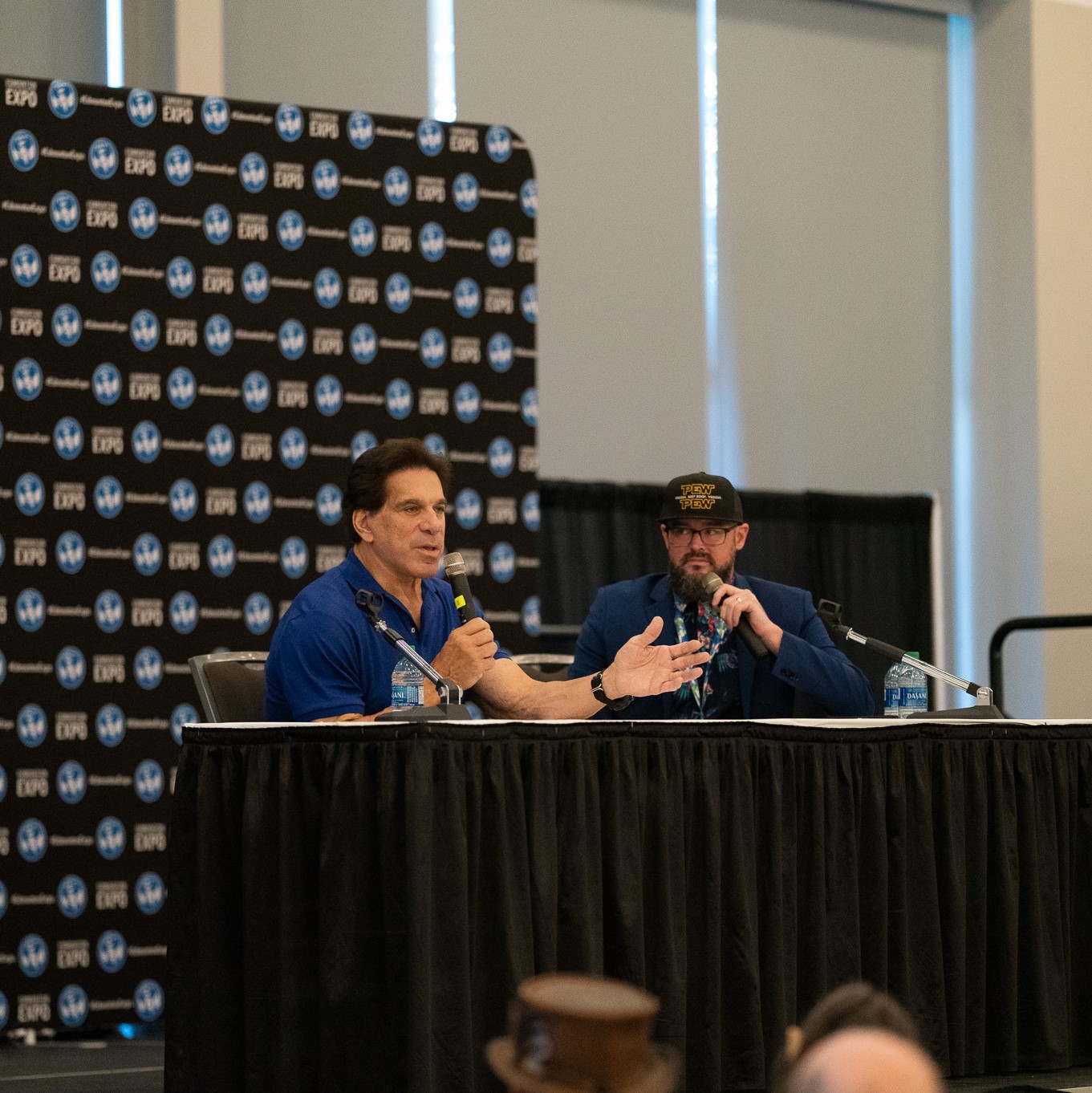Lou Ferrigno sitting at a table and talking into a microphone