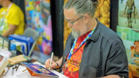 A comic creator is sketching at his table