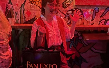 woman cosplaying as a hobbit, smiling, and holding a FAN EXPO Dallas merchandise bag