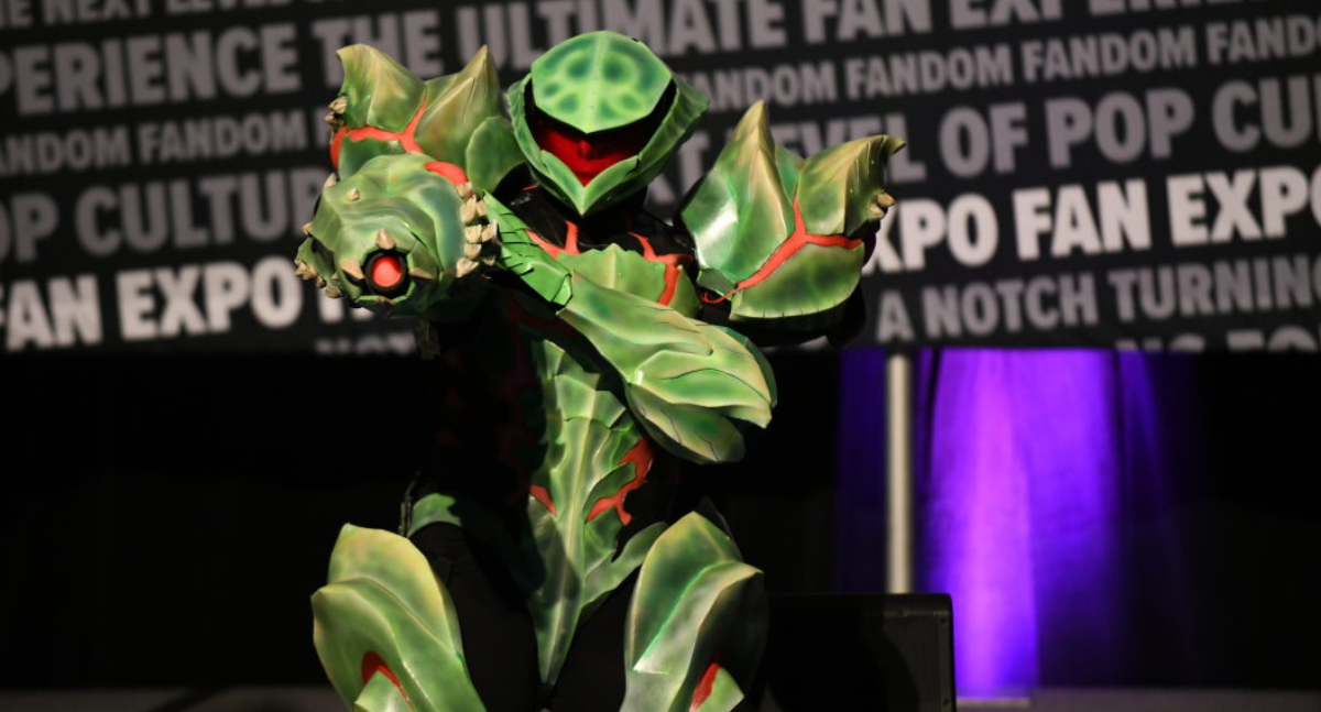 A large green droid with glowing blaster pointed at the camera. the red fiery accents pop against the deep green mechanics