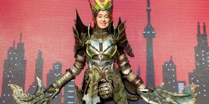 Cosplay Grand Prix winner on the main stage, in front of the red LED screen - their cosplay is Acidic Glavenus Armour