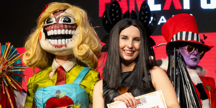 Left to right: A cosplay dressed as Miss Delight from Poppy Playtime 3, a personified Toothless from How to Train Your Dragon, and the Valention cosplayer. Toothless smiles at the camera as the Miss Delight stares forward.