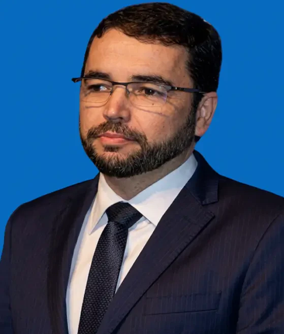 Antônio Bastos, palestrante em evento de saúde, usando terno, gravata e óculos sobre fundo azul.