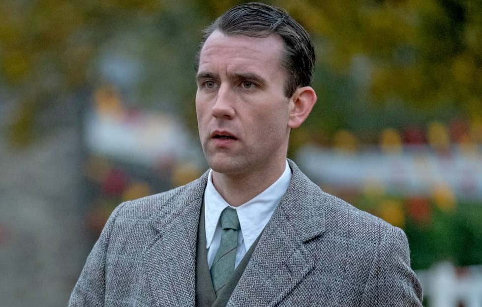 Looking dapper, Matthew is wearing a gray tweed suit with a green tie.