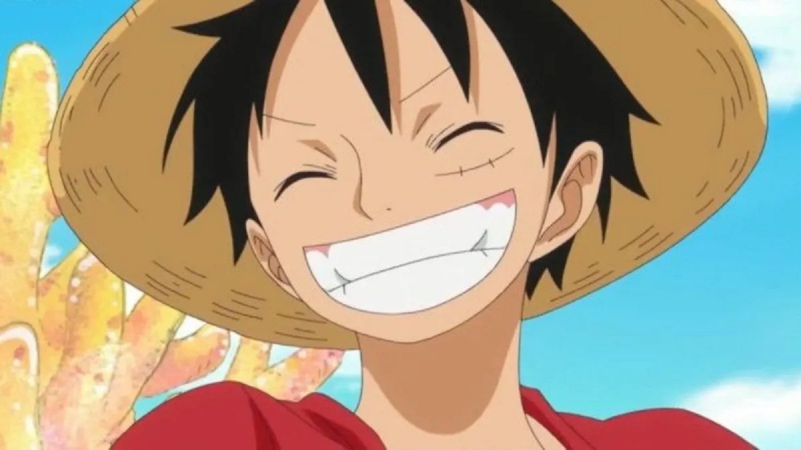 Luffy, smiling wide with his eyes closed, has a scar under his right eye and wears his signature yellow straw hat and red vest.