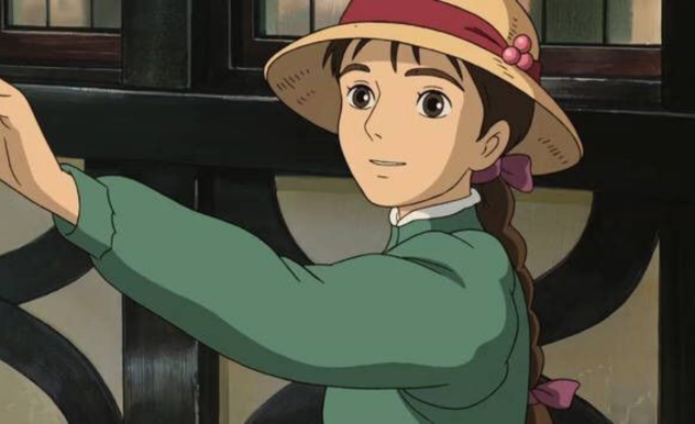 Sophie, wearing a long sleeved green dress and wicker sunhat, smiles into the distance as she begins to board her train.