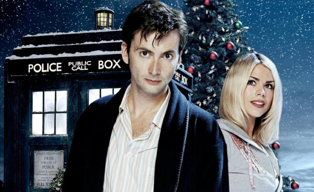 Rose and The Doctor pose in front of the TARDIS. Behind the TARDIS stands a tall Christmas tree with gold tinsel and red baubles.