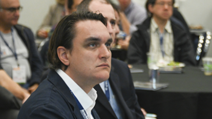 Man in blue suits listening to conference presentation